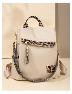 Detail of beige Oxford fabric backpack featuring leopard print panels and metal tassels