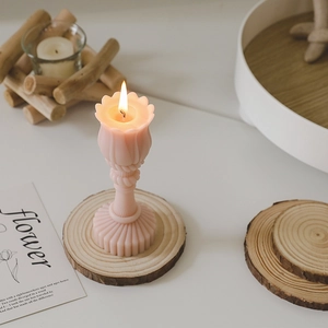 Pink flower shaped scented candle on a rustic wood base for home decoration