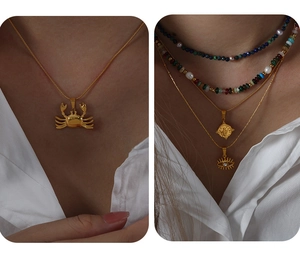 Detailed view of layered necklaces featuring gold crab and evil eye pendants with beads