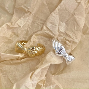 Close-up of S925 sterling silver bow rings with detailed textured finish in gold and silver