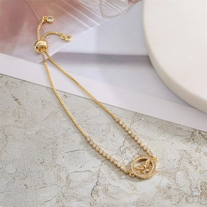 Detail of adjustable gold bracelet featuring a bird pendant and sparkling zircon accents