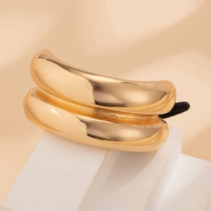 Detail of a polished gold double-layered curved hair cuff with black elastic band