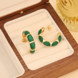 Vintage gold-plated C-shaped hoop earrings with green enamel on a display box