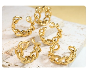 Detailed view of five gold chain-style open rings on a beige travertine stone surface