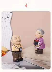 Dettaglio di figurine di coppia anziana in resina con macchina fotografica e fiori