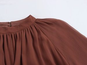 Dettaglio dello scollo in chiffon marrone con delicate pieghe a balze e cuciture rifinite