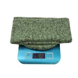 Winter knitted beanie in green and black blend showing 102g weight on a digital scale
