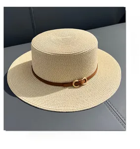 Detail of beige flat top straw boater hat with brown leather band and gold buckle