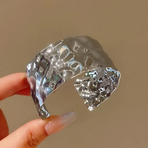 Bracciale rigido argento con trama martellata irregolare tenuto in una mano
