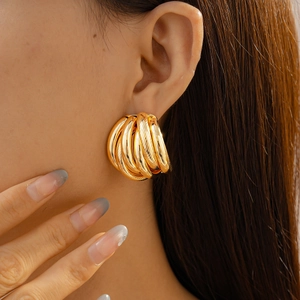 Close-up of elegant gold multi-layered textured geometric hoop earrings on a model