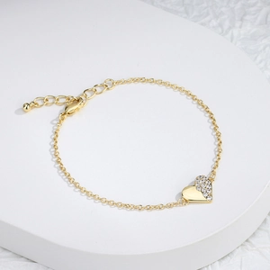 Elegant gold heart bracelet with sparkling cubic zirconia on a minimalist white stand