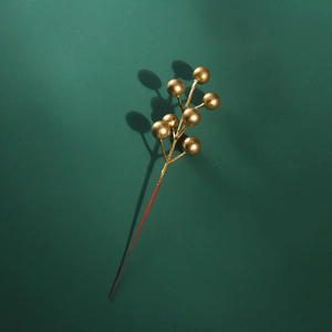 Detailed view of golden Christmas artificial berry branch on deep green background