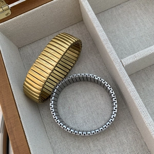 Gros plan de bracelets extensibles dorés et argentés dans un coffret à bijoux en bois