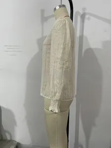 Close-up of white long sleeve blouse with elegant floral lace embroidery and ruffled cuffs