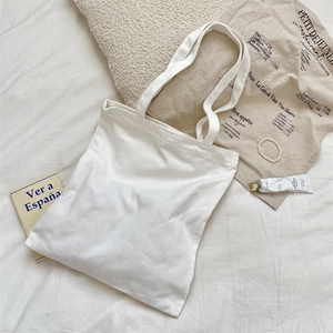 Flat lay of a white canvas tote bag with French linen and lifestyle accessories