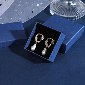 Close-up of baroque pearl earrings with gold-plated zircon setting in a premium blue gift box