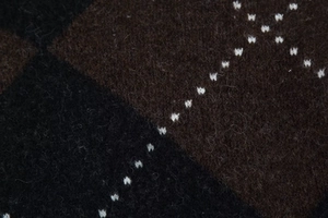 Macro shot of dark brown knit fabric with diagonal textures and white cross stitching