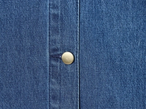Dettaglio del tessuto della giacca di jeans con colletto in velluto e bottone
