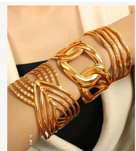 Macro detail of layered 18K gold plated wide textured bangle and geometric V bracelet set