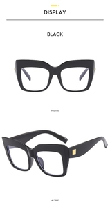 Close-up of black oversized cat-eye glasses frame with gold square metal accents