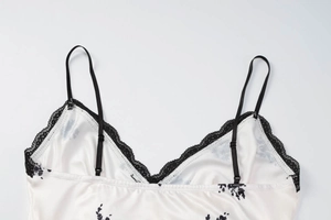 Détail de la robe nuisette en satin blanc avec imprimé floral et dentelle noire au col