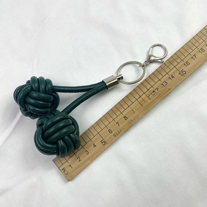 Dark green leather monkey fist keychain with woven ball design and silver metal rings