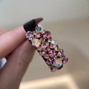 Gros plan de strass roses et champagne sur une pince à cheveux noire élégante