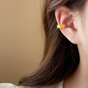Close-up of gold-plated ear cuff featuring a bow design with zircon and white star accents