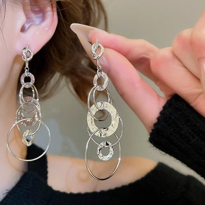 Close-up of silver knot tassel earrings with layered hammered texture on female model