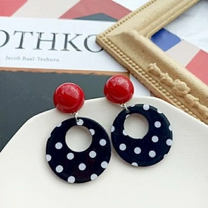 Close-up of French Baroque earrings with red studs and black white polka dot rings