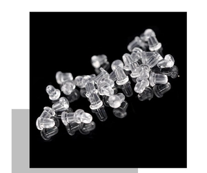 Macro shot of clear silicone earring backs scattered on a black reflective surface