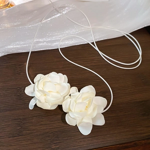 Détail d'un accessoire floral en satin blanc fait main avec cordon sur bois