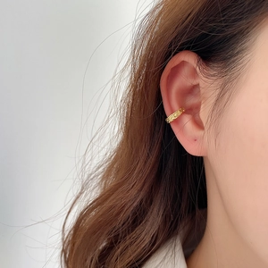 Detailed view of gold ear cuff with irregular lava texture on model's ear