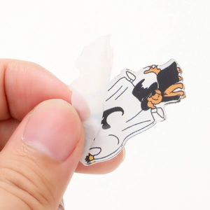 Peeling protective film from cartoon acrylic Halloween keychain with bat and pumpkin motifs
