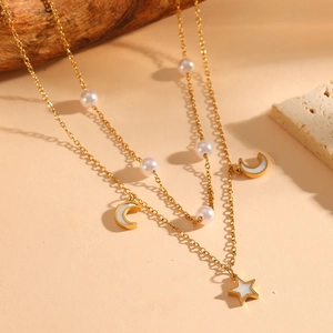 Detail of double-layered gold necklace with star, moon pendants and white beads