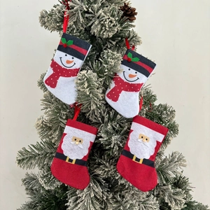 Close-up of four mini Christmas stocking cutlery holders hanging on a snow-tipped tree branch