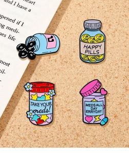 Detail view of 4 colorful enamel pill jar pins with funny text on a cork background