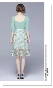 Detail of light green knit top and floral embroidered mesh skirt on a fashion model