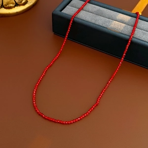 Gros plan d'un collier de perles en cristal rouge facetté posé sur un écrin à bijoux