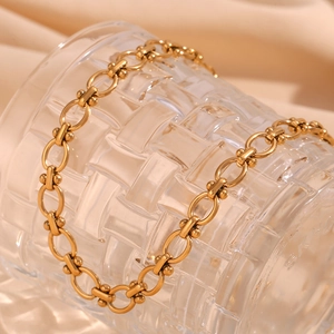 Detail einer 18K vergoldeten Gliederkette mit ovalen Elementen auf Seidenstoff am Glas