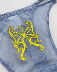 Close-up of intricate yellow butterfly embroidery on blue sheer mesh lace thong