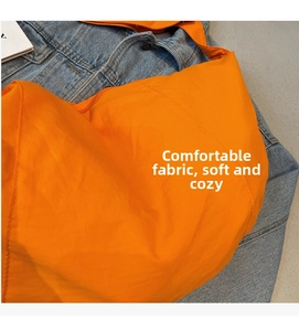 Detail of soft orange nylon fabric texture on a large capacity crossbody dumpling bag