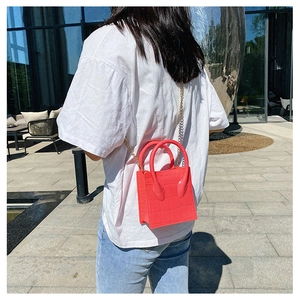 Detailed view of a red crocodile pattern crossbody bag with a golden chain strap and top handle