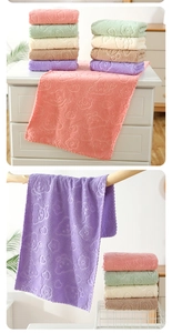 Close-up of soft coral fleece towels with bear and heart embossed patterns in various colors