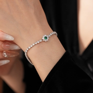 Detailed view of silver flower bracelet with green gemstone and sparkling zircons on wrist