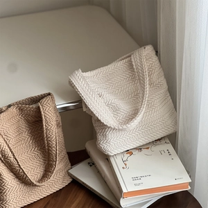 Close-up of the woven herringbone texture on beige and brown knit tote bags