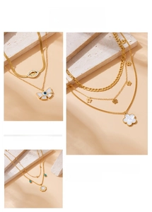 Detail of layered gold stainless steel necklaces with daisy and evil eye pendants