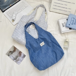 Gros plan sur des sacs cabas à carreaux bleu et gris avec étiquettes de marque en tissu
