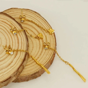 Minimalist gold tassel earrings with zircon studs and heart or bar charms on wood base