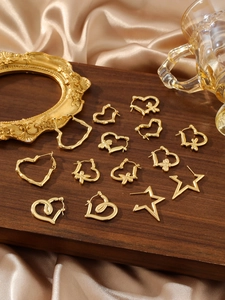 Detaillierte Nahaufnahme goldener Herz- und Sternohrringe auf luxuriösem Satin